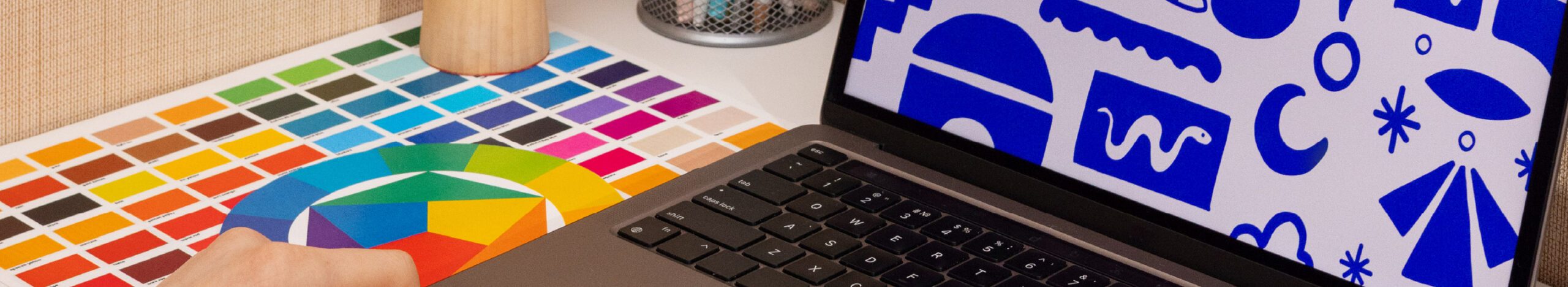 Canva print bleed. designers desk with colour chart and colour illustration visible on laptop screen